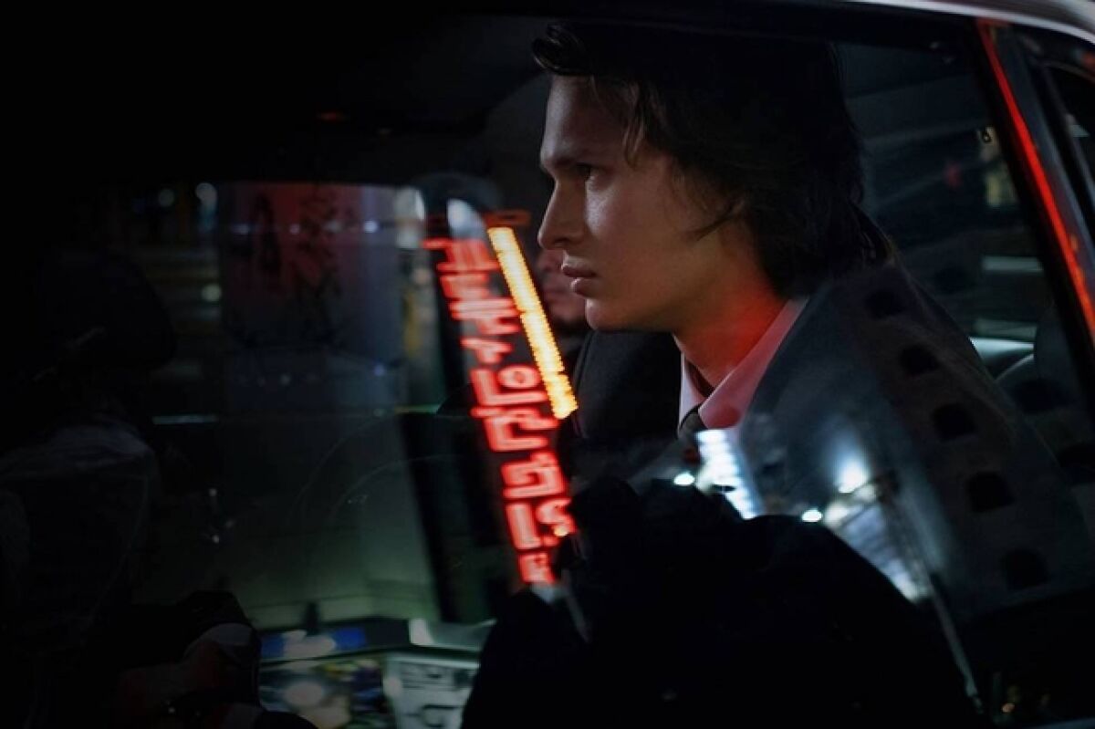 A man rides in a car through Tokyo's neon lights