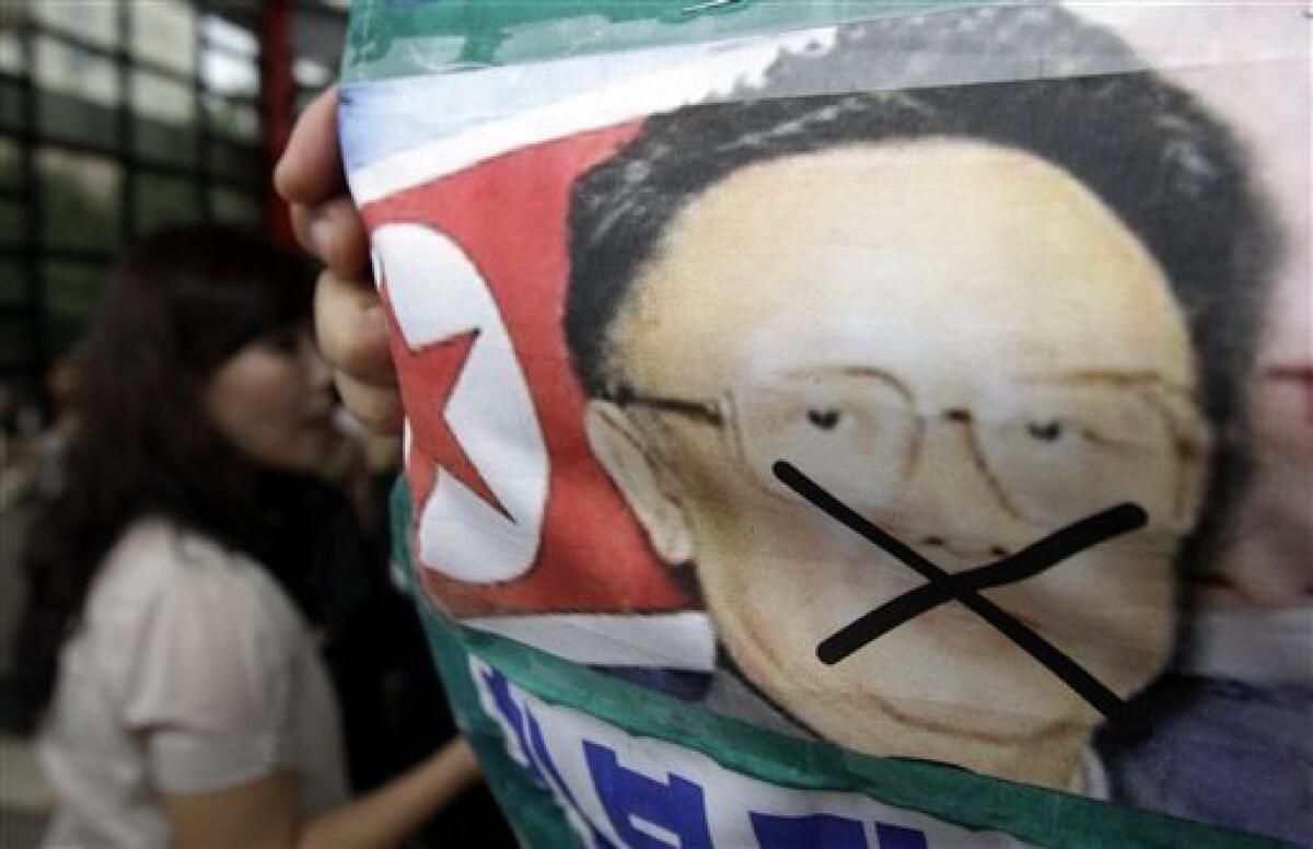 A woman walks by a North Korean flag attached with a picture of North leader Kim Jong Il during a rally held against pro-North Korean groups in Seoul, South Korea, Thursday, Sept. 9, 2010. The youngest son of leader Kim Jong Il is widely expected to make his public debut as the Dear Leader's heir apparent at a rare Workers' Party convention, the nation's biggest political gathering in 30 years. (AP Photo/ Lee Jin-man)