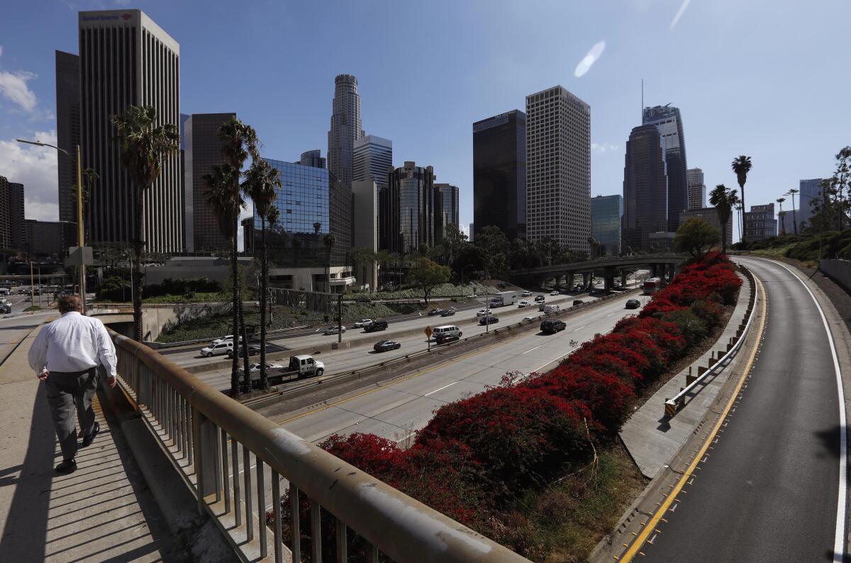 A pedestrian crossed a freeway with few cars.