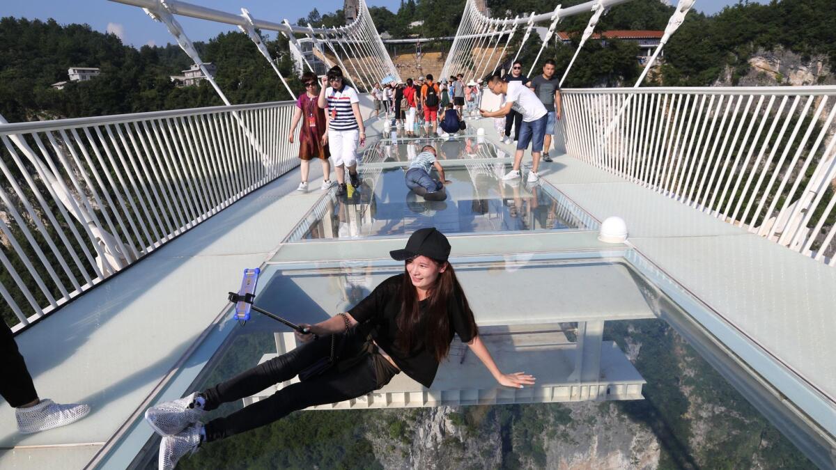 A tourist takes a selfie on the glass-bottom bridge over China's Zhangjiajie Grand Canyon.