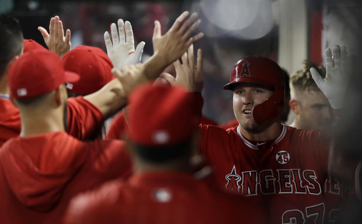 El jugador de los Angelinos de Los Ángeles Mike Trout (derecha) recibe la felicitación de sus compañeros tras sacudir un vuelacercas solitario en el tercer inning del juego de la MLB que enfrentó a su equipo con los Medias Blancas de Chicago, el 15 de agosto de 2019, en Anaheim, California. (AP Foto/Marcio Jose Sanchez) ** Usable by HOY, ELSENT and SD Only **