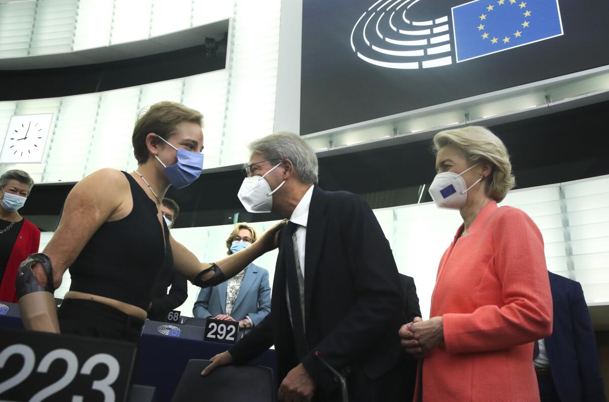 European Commissioner for Economy Paolo Gentiloni, center, and European Commission President Ursula von der Leyen, right, speak with speak with Tokyo 2020 Paralympic gold medallist Beatrice Vio at the European Parliament in Strasbourg, France, Wednesday, Sept. 15, 2021. The European Union announced Wednesday it is committing 200 million more coronavirus vaccine doses to Africa to help curb the COVID-19 pandemic on a global scale. (Yves Herman, Pool via AP)