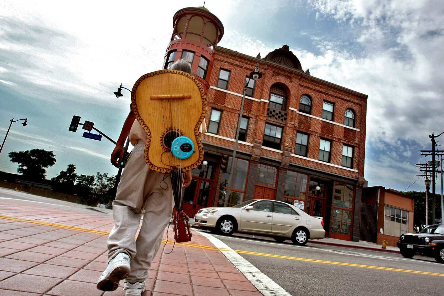 Mariachi Beto Lopez, 55, walks toward the Boyle Hotel with a guitarrón on his back. Though Lopez doesn't live there, the hotel, known for its long history of housing mariachis, has been restored and is again open to residents, including mariachis. The restored cupola and refurbished red bricks help the hotel maintain its title as the "jewel" of Boyle Heights.