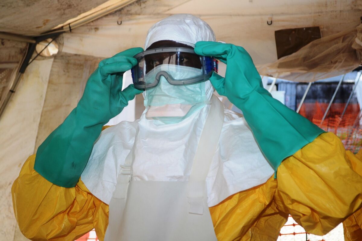 A member of Doctors Without Borders dons protective gear June 28 at the isolation ward of the Donka Hospital in Conakry, Guinea, treating Ebola patients.