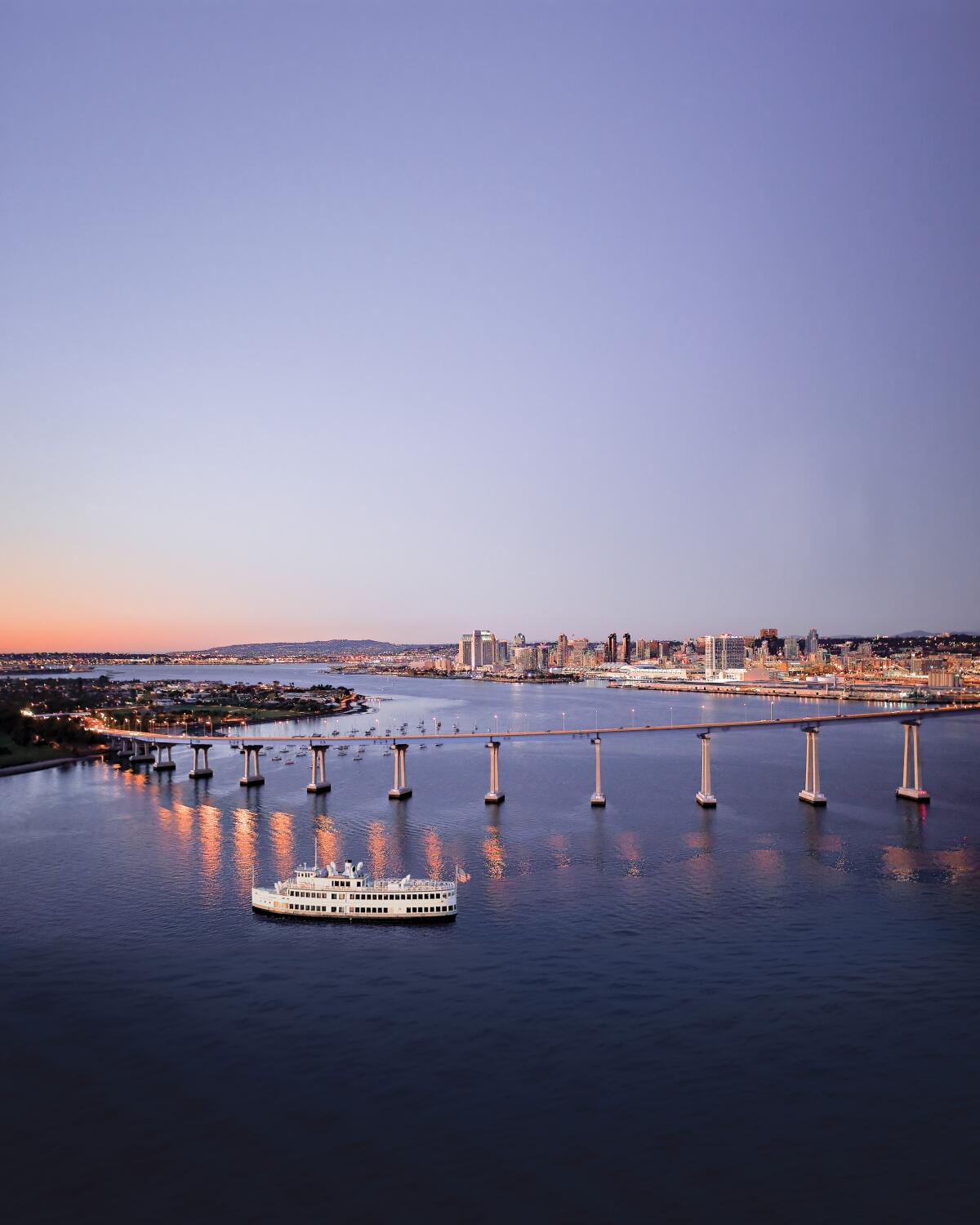 A Hornblower Cruises boat passes the Coronado Bridge in San Diego Harbor