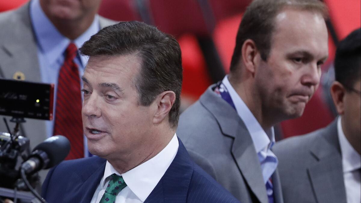 Then-Trump campaign chairman Paul Manafort, and Rick Gates, right, are surrounded by reporters on the floor of the Republican National Convention in Cleveland on July 17, 2016.