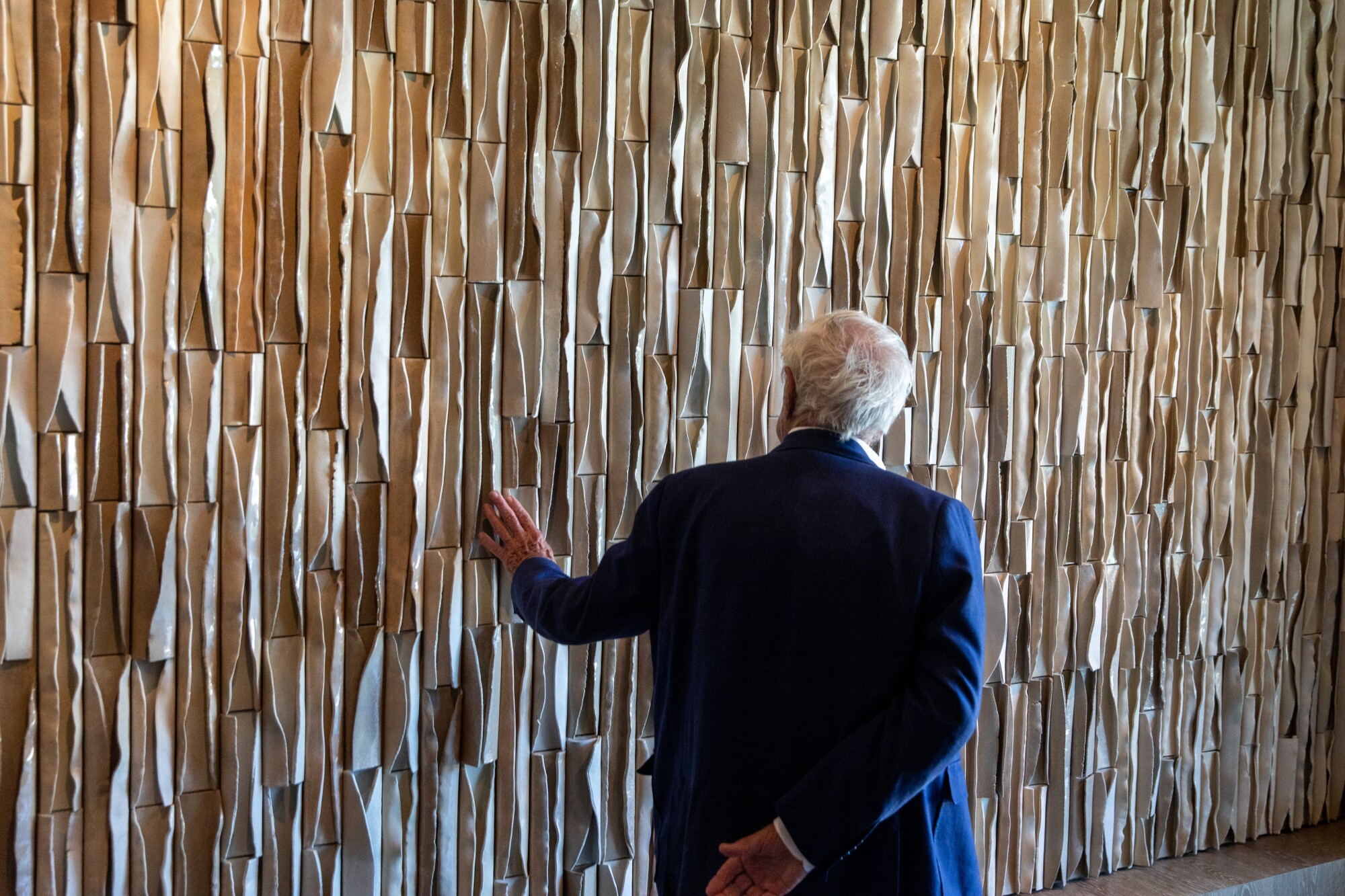 Architect Frank Gehry runs his hand on a wall of stoneware by artist Ben Medansky.