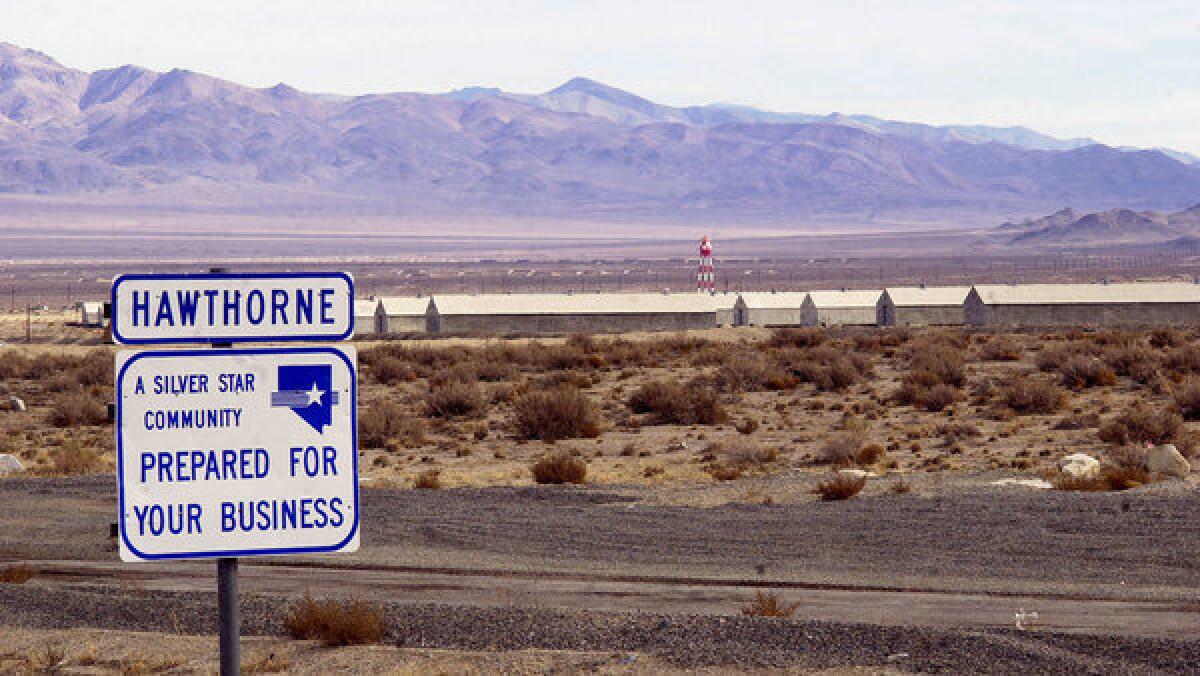 A sign along the highway promotes Hawthorne, Nevada as ready for business against a backdrop of munitons bunkers at the Hawthorne Army Depot.
