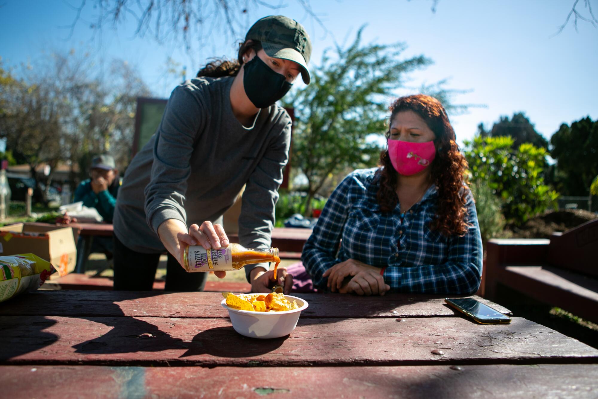 Elizabeth Christy, Program Manager at La Madera Community Garden, pours Small Axe Peppers sauce over some chips