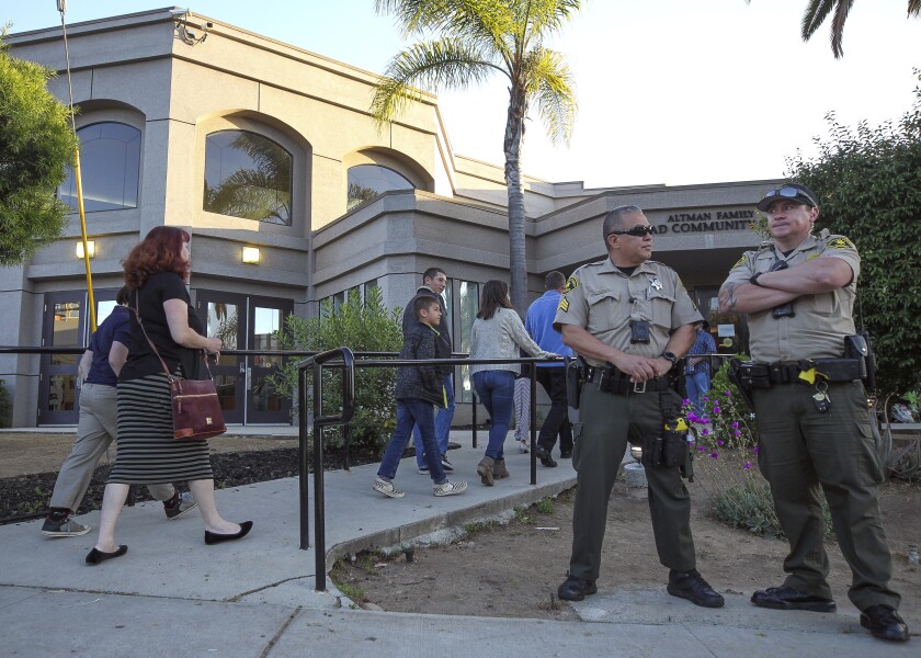 People enter Chabad of Poway as two San Diego County sheriff's deputies stand guard