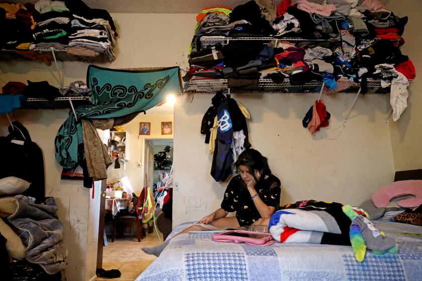 LOS ANGELES, CA - JUNE 15: Angie Davila, 20, the oldest of six children, finds quiet time for herself in the family's one-bedroom apartment in the Pico-Union neighborhood on Wednesday, June 15, 2022 in Los Angeles, CA. There are eight family members sharing a one bedroom unit. Magdalena Garcia, 40, and husband Edgar Galicia, 48, live with their six children in a one-bedroom apartment. Magdalena has lived in the unit over 20 years. Overcrowded housing in Pico-Union, considered the most overcrowded neighborhood in Los Angeles. (Gary Coronado / Los Angeles Times)