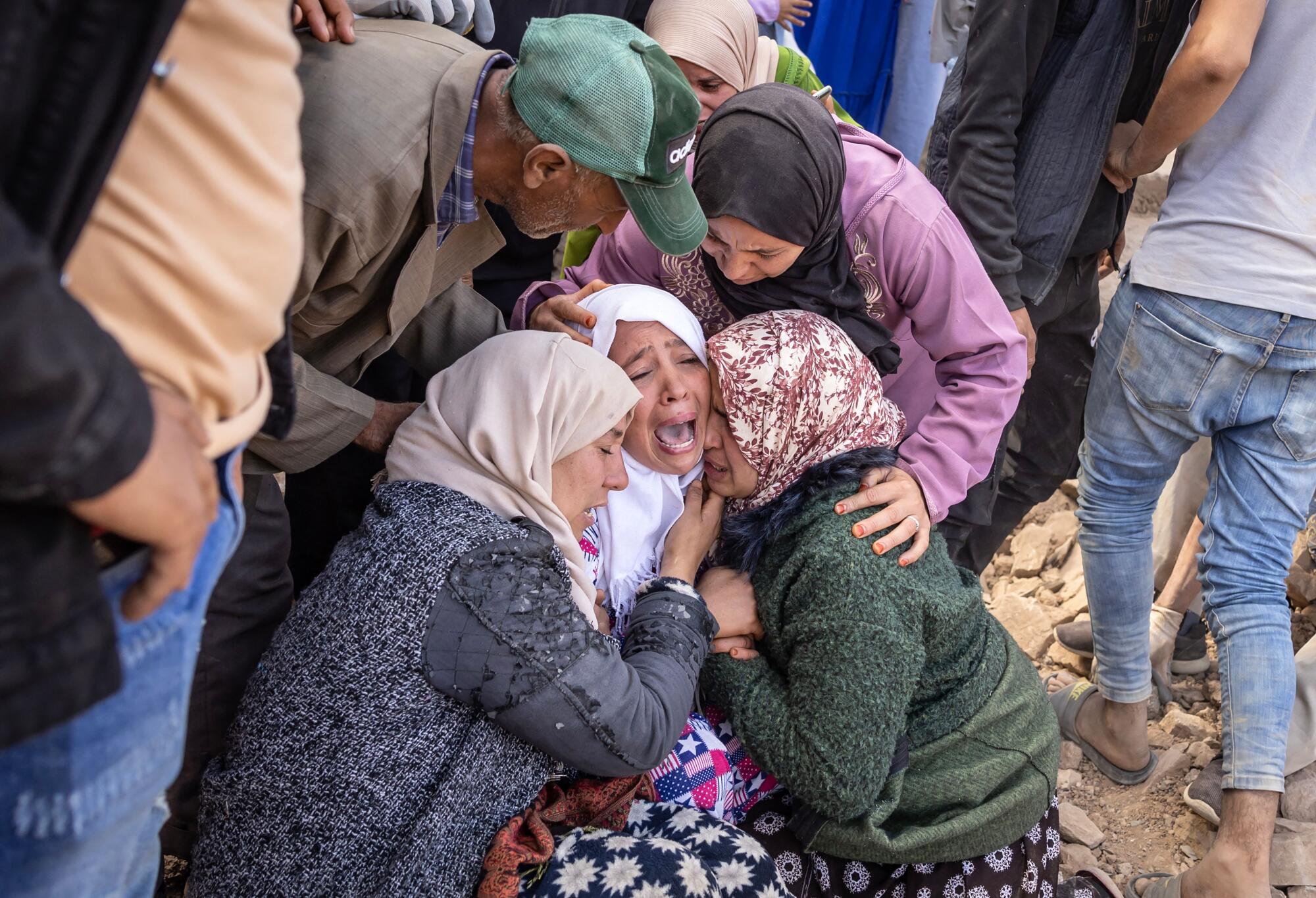 Women cry as volunteers recover the body of a family member from the rubble of collapsed houses.