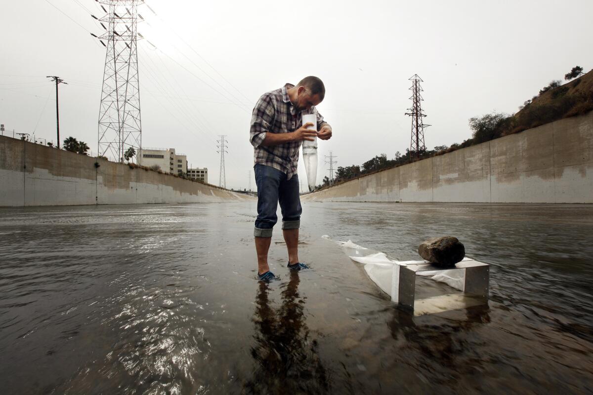 Environmental activist and scientist Marcus Eriksen collects a sample in 2014 of plastic particles making their way via the Los Angeles River to the ocean, where some will join the sediment. Some scientists say plastic deposits and other detritus of human development mark the beginning of a new geologic era.
