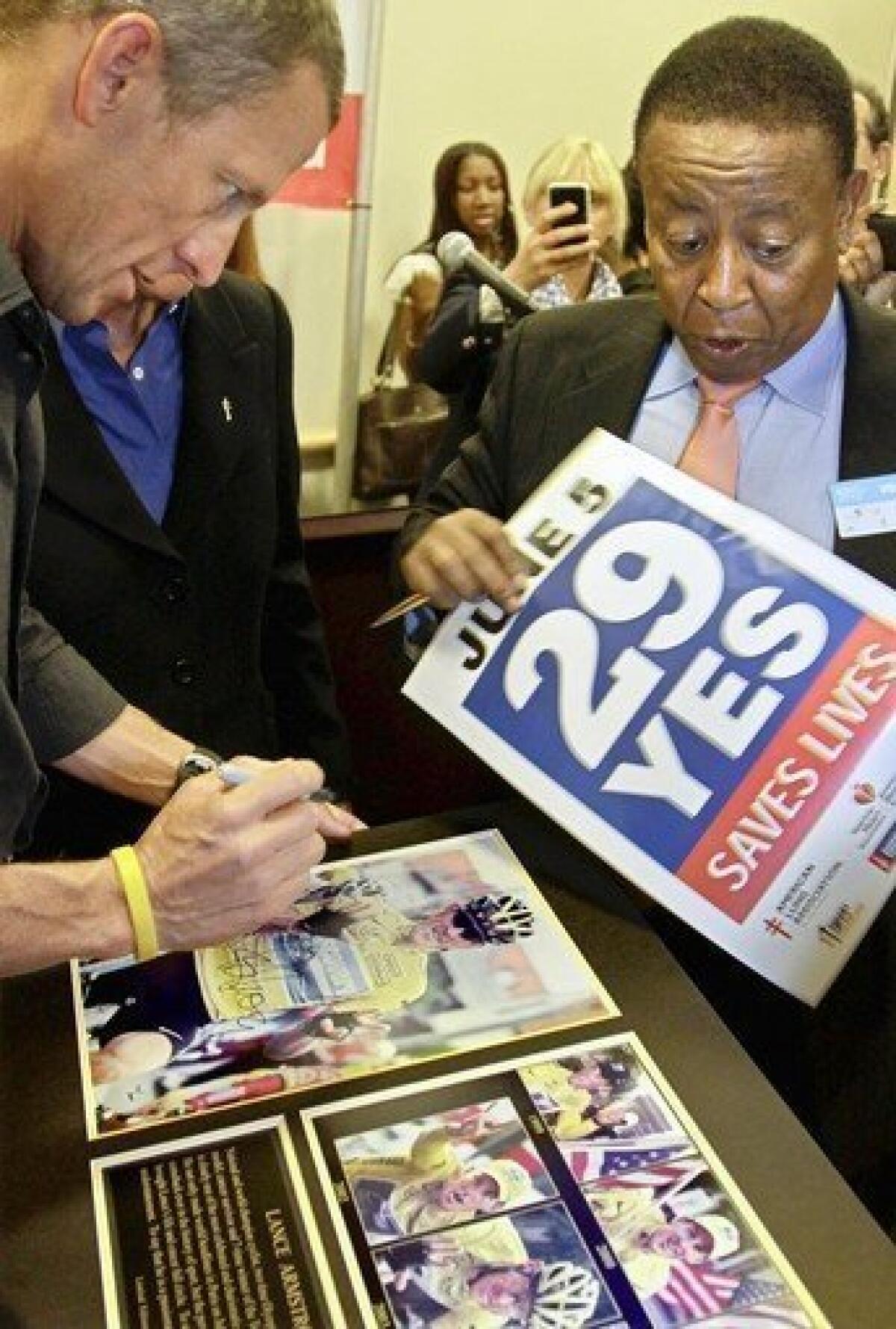 Lance Armstrong, left, signs an autograph for Proposition 29 supporter Yesewlik "Leo" Ayalew. Armstrong has donated $1.5 million to the Proposition 29 campaign.