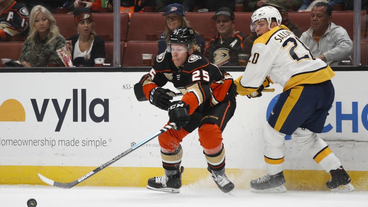 Ducks' Ondrej Kase, center, of the Czech Republic, reaches for the puck against Nashville Predators' Miikka Salomaki, of Finland, during the second period.