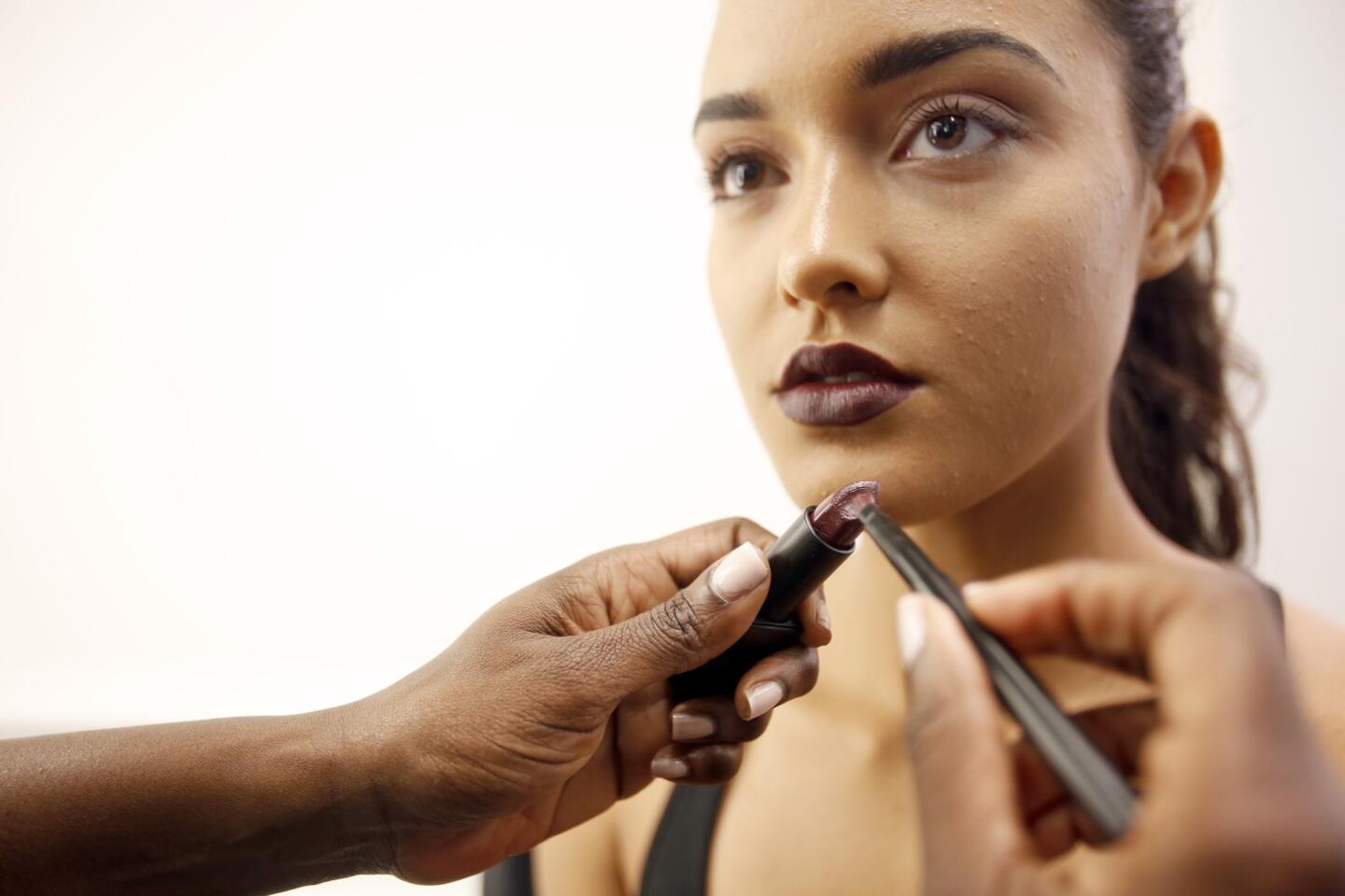 A precision lip brush is used to apply a deep eggplant shade, to control opacity.