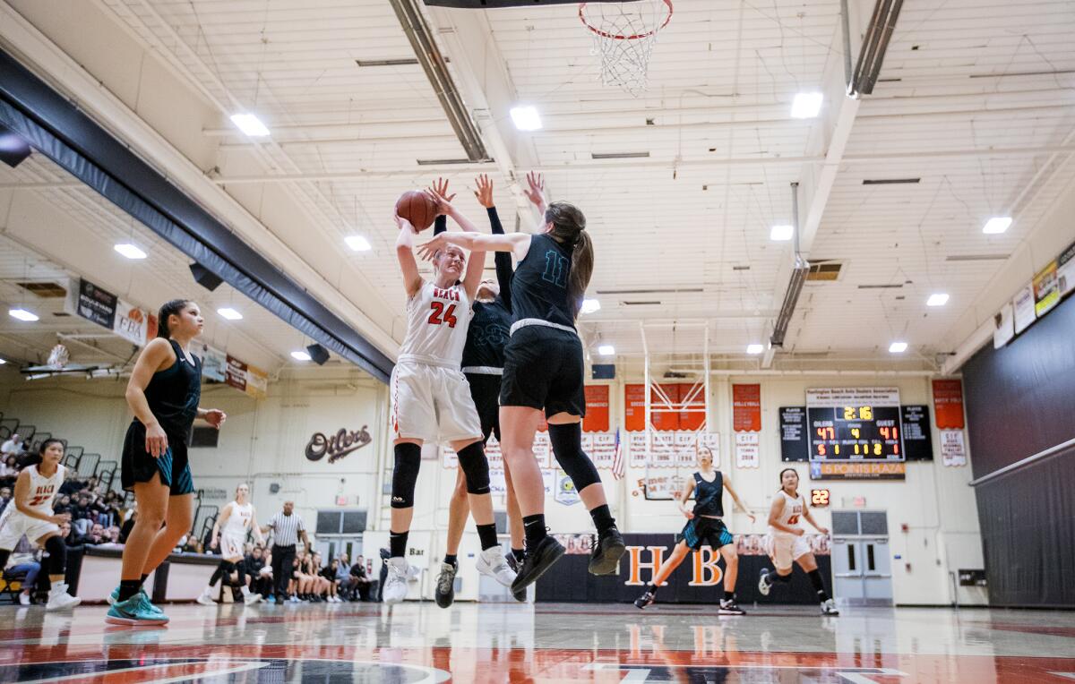 Huntington Beach's Andie Payne (24) goes up for a shot against Aliso Niguel's Catherine Swanson, center, and Sarah Matossian, right, during the first round of the CIF Southern Section Division 1 playoffs on Thursday.