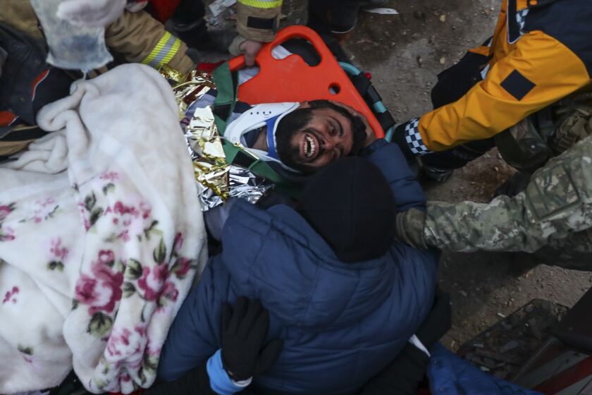 Ergin Guzeloglan, 36, is carried to an ambulance after being pulled from the rubble of a building in Hatay, Turkey.