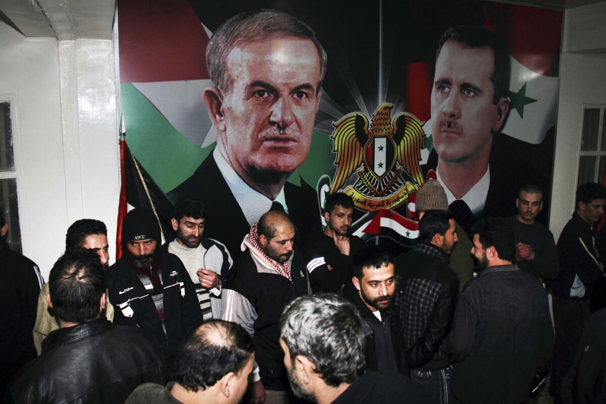 Detenidos sirios liberados se reúnen frente a carteles que muestran al presidente sirio Bashar Assad