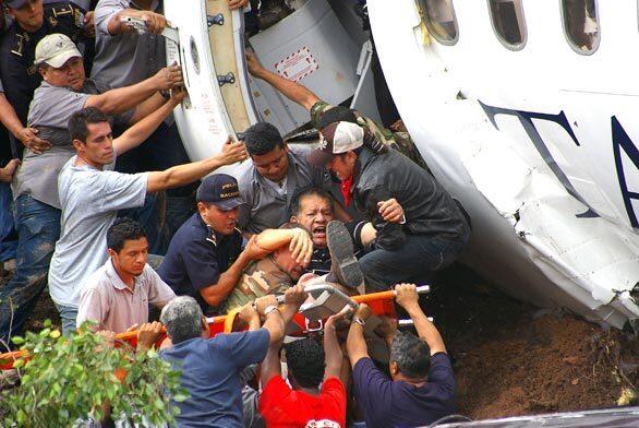 A man is carried from the inside of the Grupo Taca plane after it overshot a runway and slammed into a busy roadway in the Honduran capital of Tegucigalpa today. Two people, including a pilot, died. At least another 18 were injured.