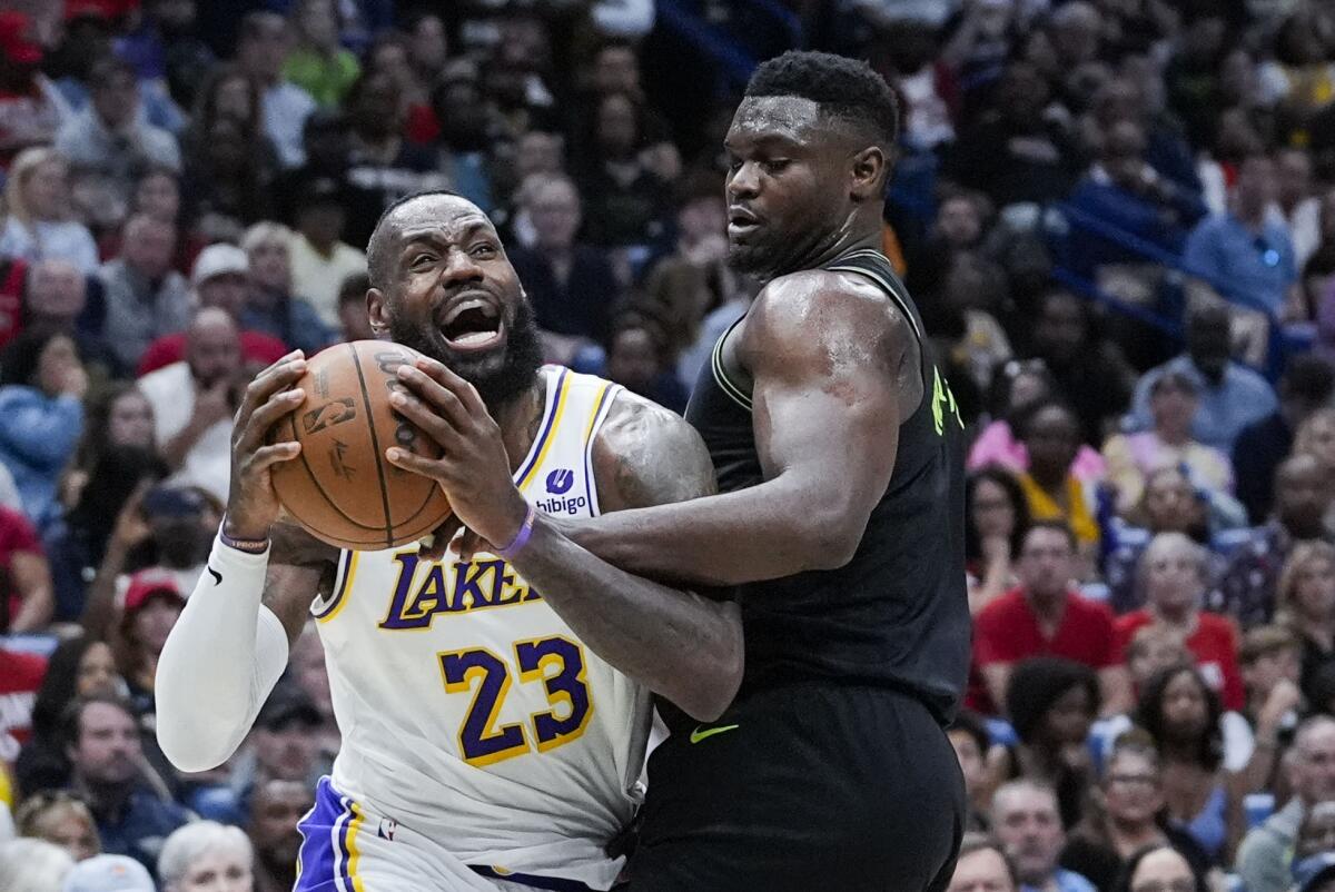 Lakers forward LeBron James, left, tries to power his way to the basket against Pelicans forward Zion Williamson.