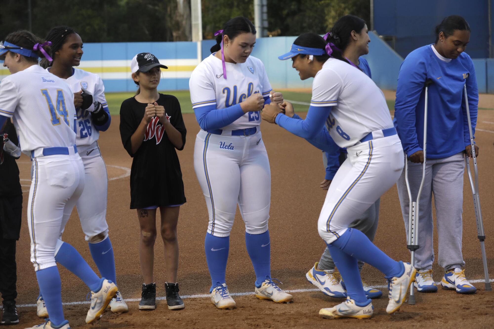 UCLA bullpen catcher Taylor Sullivan, center, is greeted by pitcher Megan Faraimo while the team is introduced to the crowd.