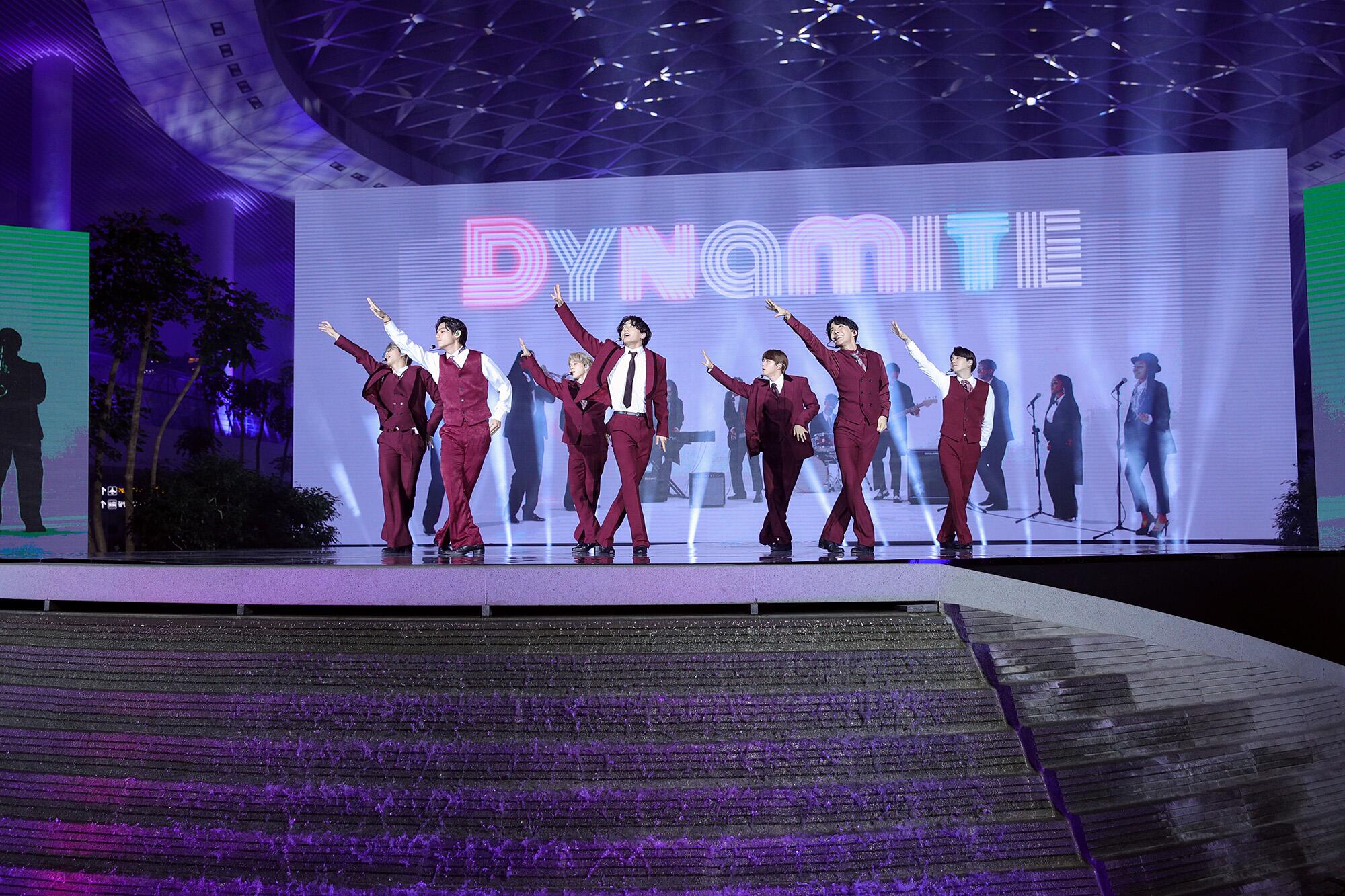 A sign reads "Dynamite" as K-pop band BTS dances.