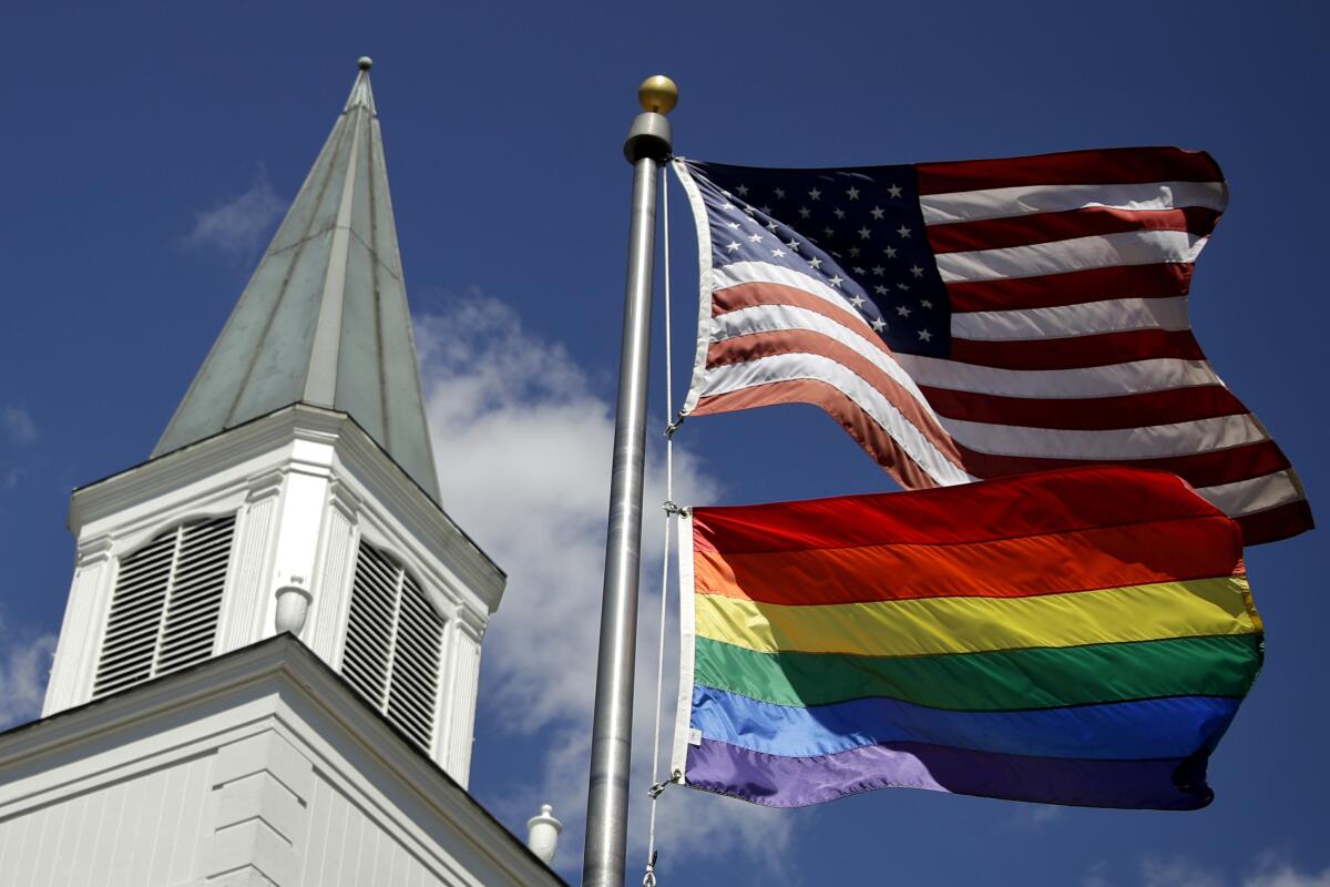 A gay pride rainbow flag flies along with the U.S. flag in front of the Asbury United Methodist Church in Kansas.