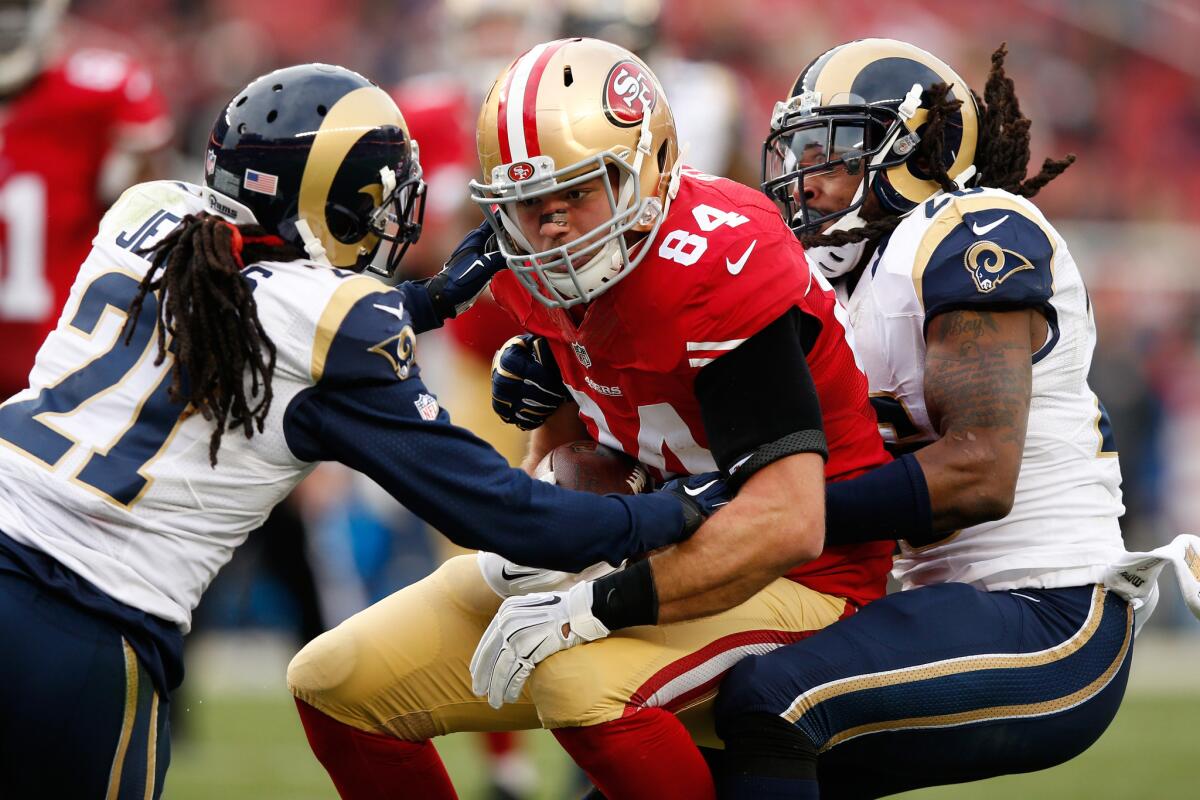 Rams defensive backs Janoris Jenkins (21) and Mark Barron (26) tackle 49ers tight end Blake Bell after a catch on Jan. 3.