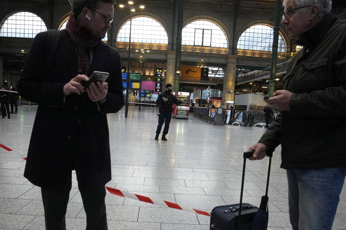 Travelers waiting behind police tape at Paris train station