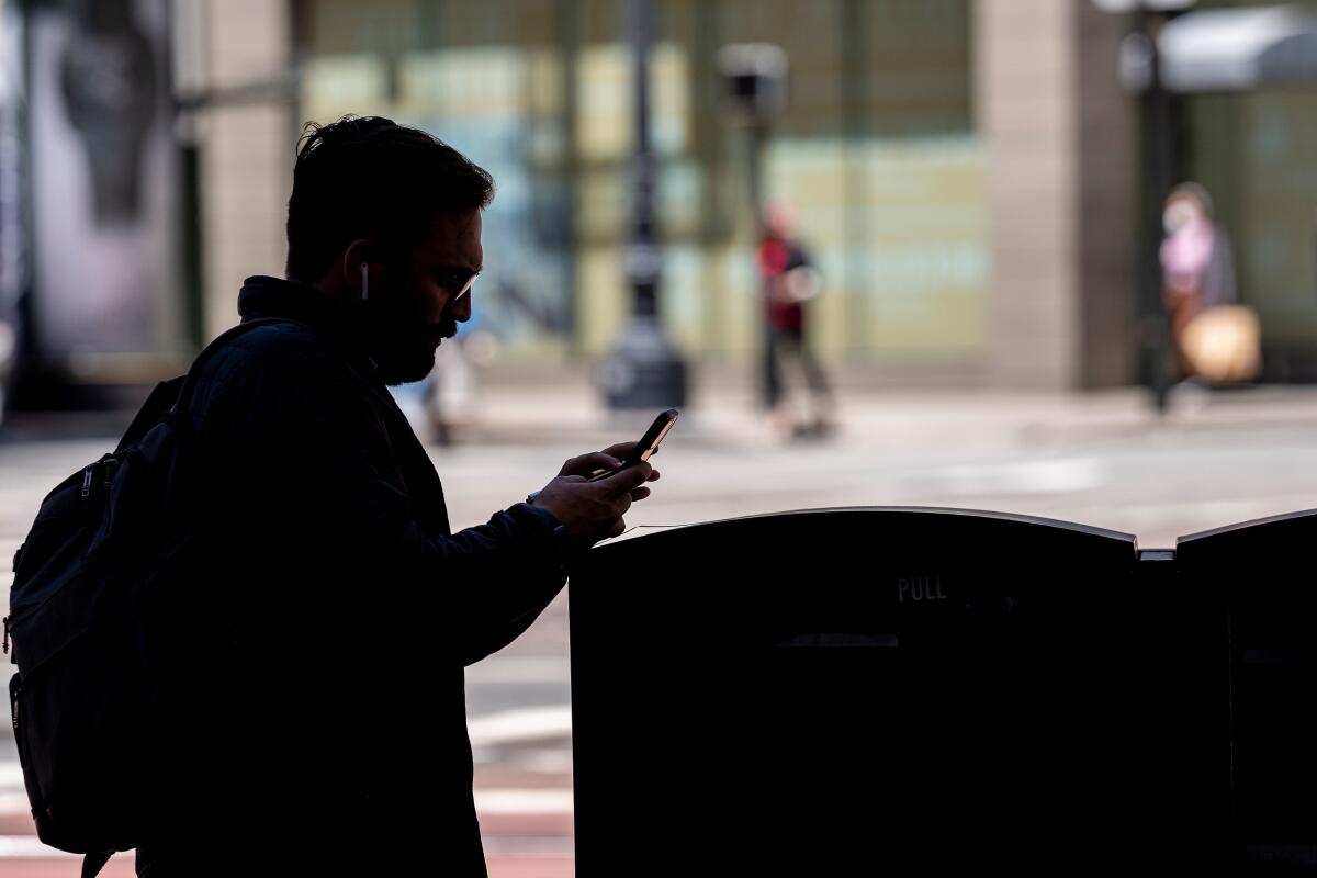 A pedestrian looks at his phone in the financial district of San Francisco.