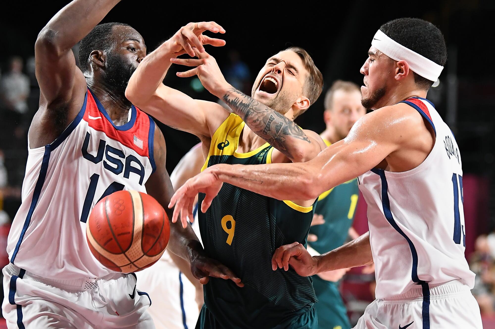 USA's Draymond Green, left, and Devin Booker strip the ball from Australia's Nathan Sobey