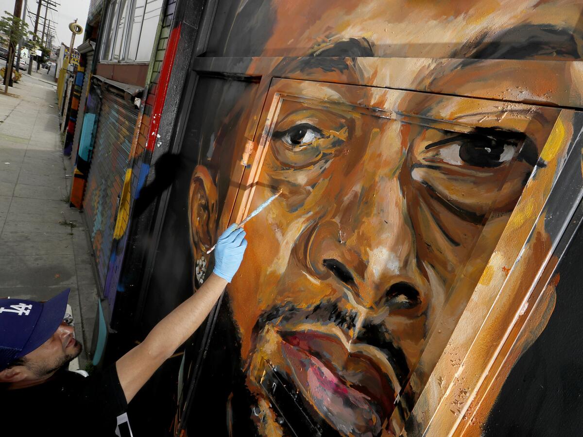 Artist Samir “Evol” Arghandwall paints a mural of Nipsey Hussle on the exterior of an art gallery at 2714 Slauson Ave. (Luis Sinco / Los Angeles Times)