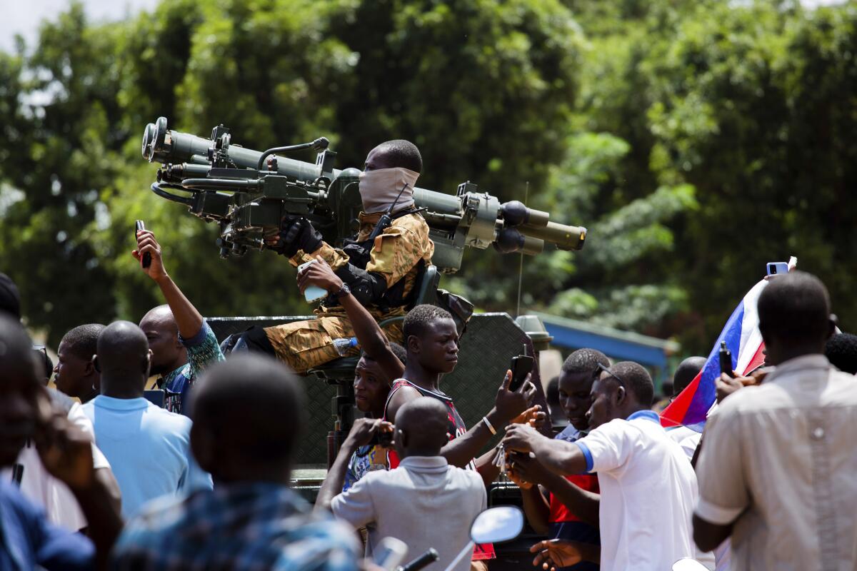 A soldier hoists a large weapon as crowds cheer.