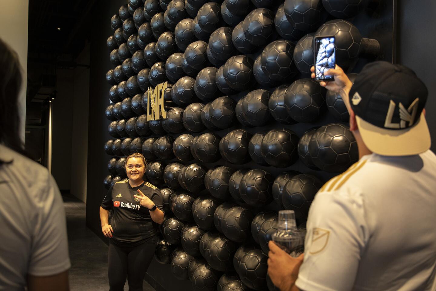 LAFC fans take selfies against a wall of soccer balls at the Figueroa Club inside the new Banc of California Stadium on April 21.