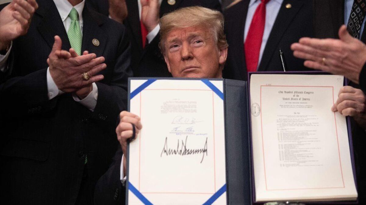 President Trump shows off his signature on the Economic Growth, Regulatory Relief and Consumer Protection Act at the White House on May 24.