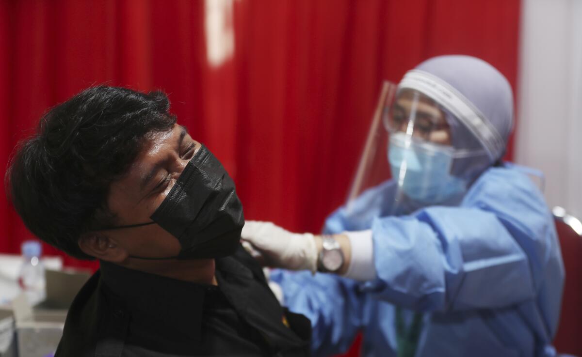 A man receives an injection of the AstraZeneca vaccine during a vaccination campaign in Bekasi outside Jakarta, Indonesia, Thursday, June 17, 2021. (AP Photo/Achmad Ibrahim)