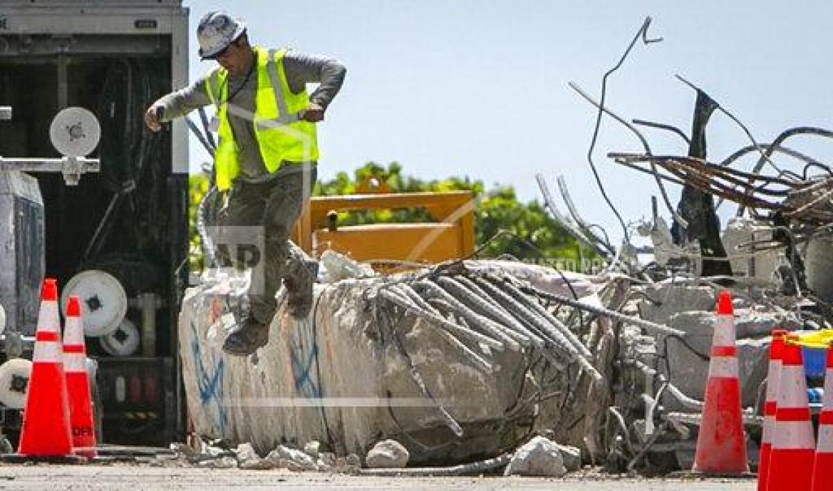 A worker jumps off a large piece of rubble on the site of the Champlain Towers South collapse
