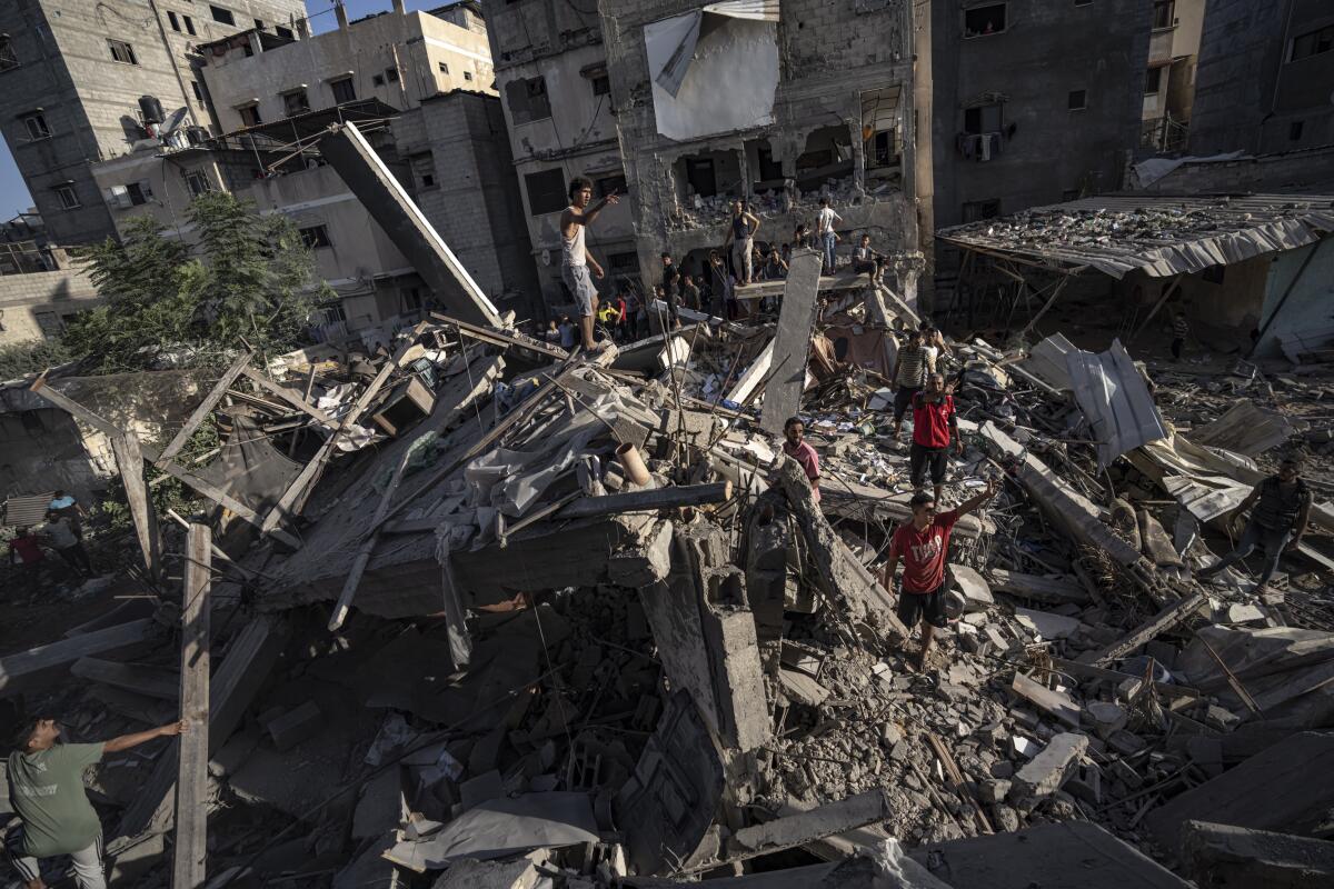People look at the destruction and debris after Israeli strikes.