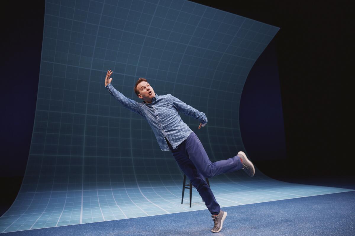 A man posing as if falling over onstage in front of a blue background