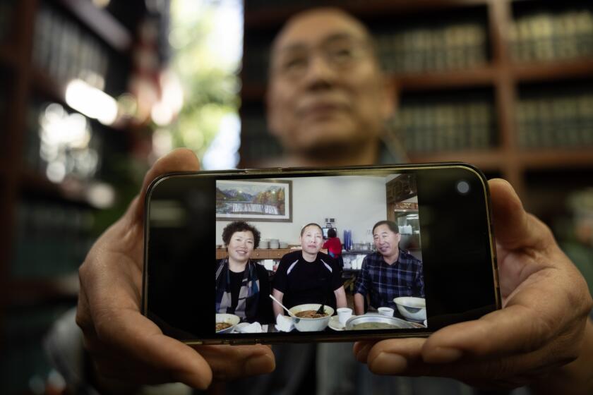 ROSEMEAD, CA - NOVEMBER 27: Yanqing Wang, the uncle of Mei Haskell, shows a picture of him, center, with his sister Yanxiang Wang, Mei's mother, and brother-in-law Li Gaoshan before their disappearance. He said he never heard any complaints about Mei Haskell's family. He had some bad feelings when he hadn't heard from his sister in almost three weeks. Photographed on Monday, Nov. 27, 2023 in Rosemead, CA. (Myung J. Chun / Los Angeles Times)
