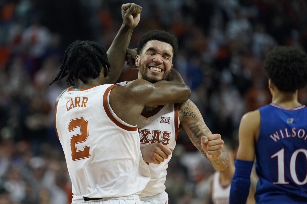 Texas forward Timmy Allen, center, celebrates the team's win over Kansas with teammate Marcus Carr (2) during the second half of an NCAA college basketball game, Monday, Feb. 7, 2022, in Austin, Texas. (AP Photo/Eric Gay)