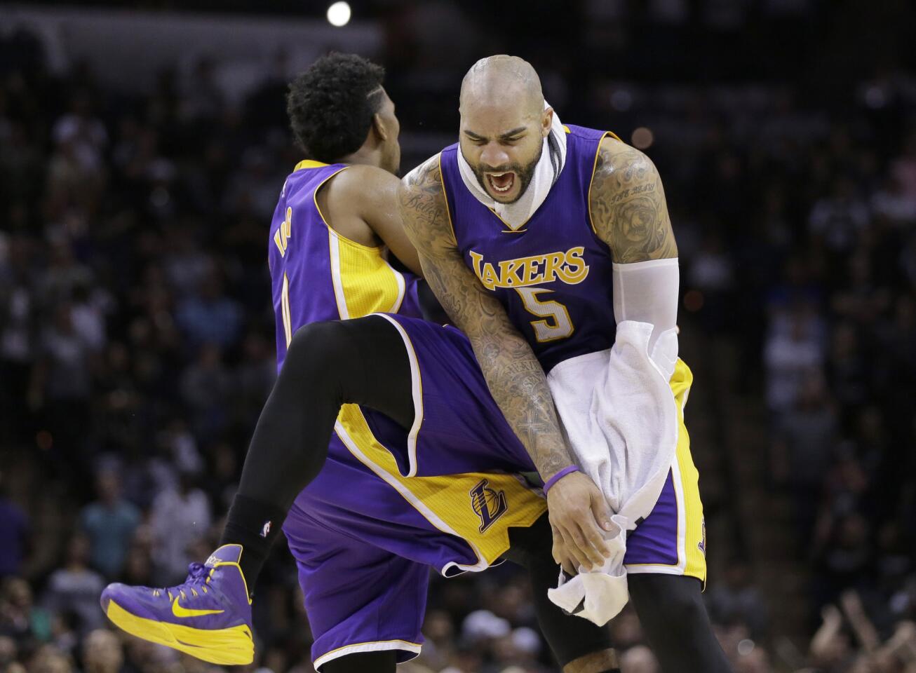 Lakers power forward Carlos Boozer (5) celebrates with teammate Nick Young after he made what proved to be the game-winning three-pointer against the Spurs with seven seconds left in overtime on Friday night in San Antonio.