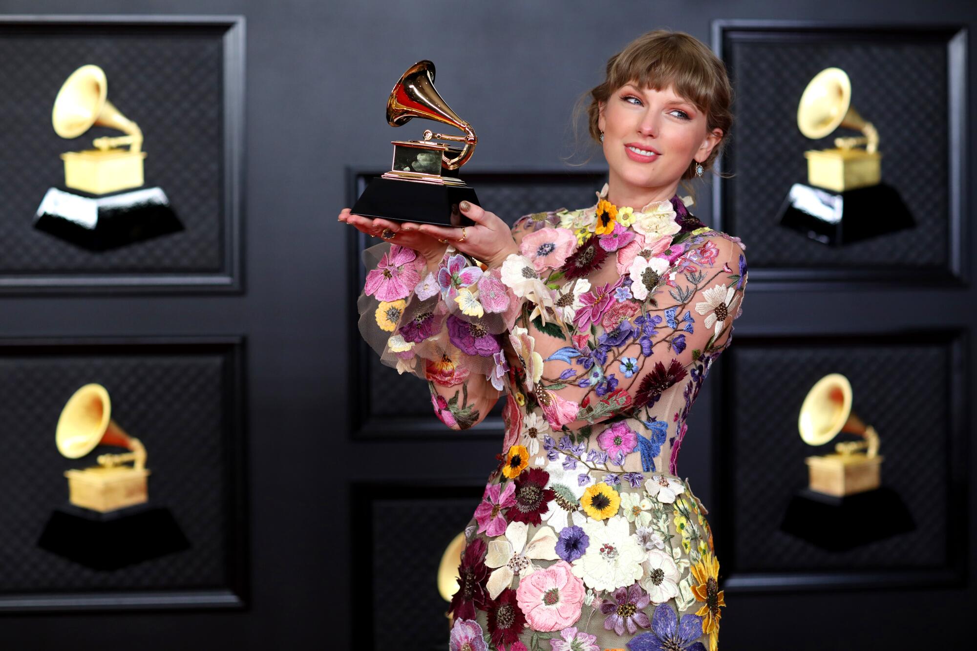 Taylor Swift holds her Grammy for album of the year.