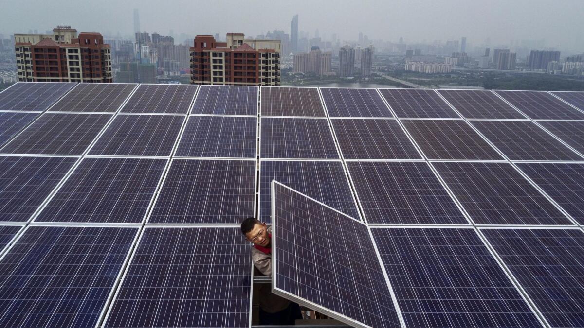 A worker from Wuhan Guangsheng Photovoltaic Co. works on a solar panel project on the roof of a 47-story building in Wuhan, China, on May 15, 2017.