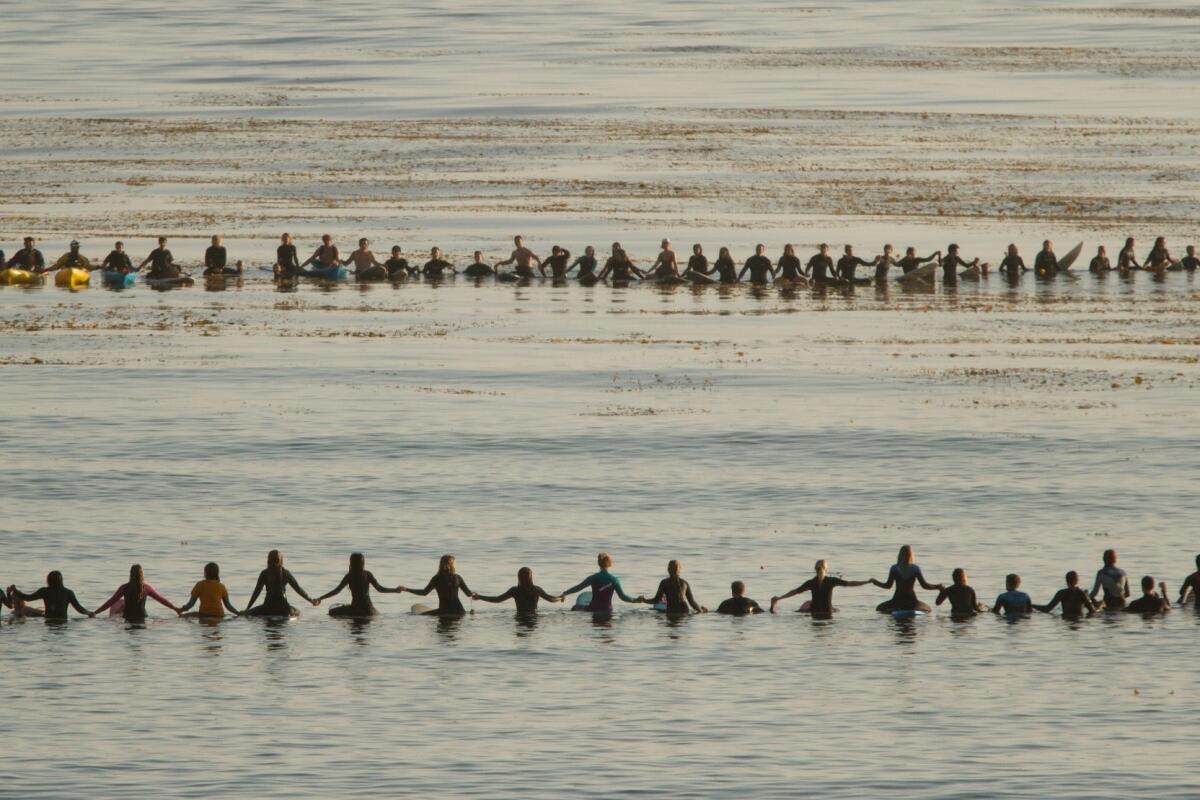 Hundreds hold hands to form a circle in the Pacific Ocean for the Memorial Paddle Out May 28 in response to the Isla Vista massacre.