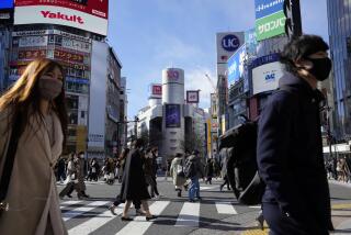 People wearing protective masks to help curb the spread of the coronavirus walk along a pedestrian crossing Friday, Jan. 21, 2022, in Tokyo. Restaurants and bars will close early in Tokyo and a dozen other areas across Japan beginning Friday as the country widens COVID-19 restrictions due to the omicron variant causing cases to surge to new highs in metropolitan areas. (AP Photo/Eugene Hoshiko)