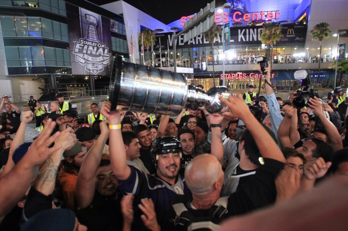 Kings fans hold a replica Stanley Cup and celebrate winning the title for the second time in three years after the Kings beat the Rangers in Game 5 of the Stanley Cup Final.