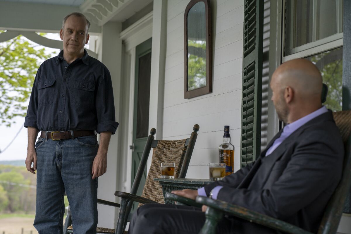 Two men talking and drinking whiskey on a porch.