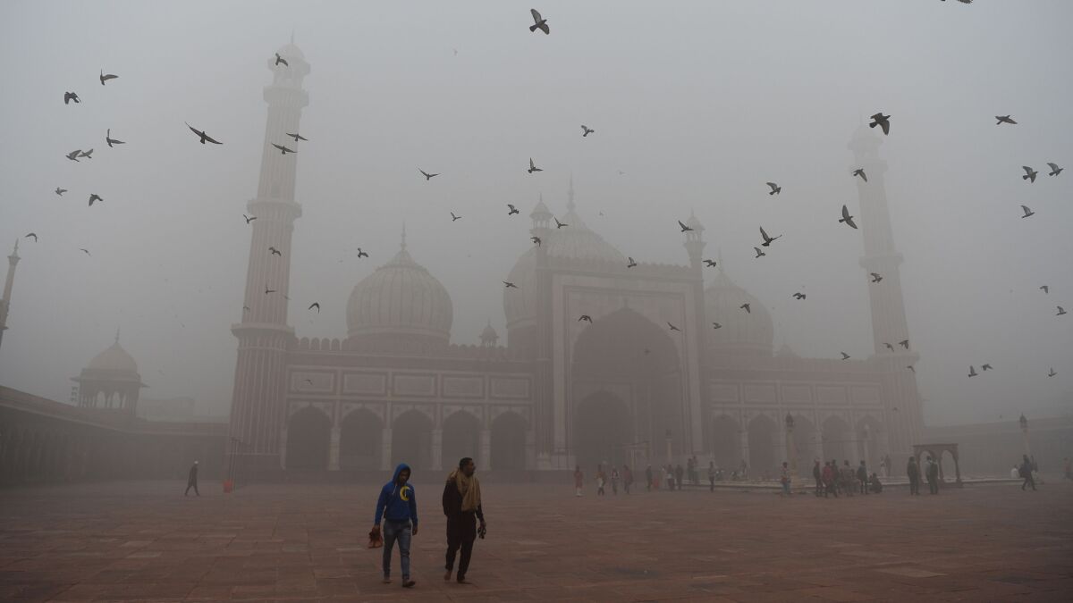 Indian visitors walk through the courtyard of Jama Masjid mosque amid heavy smog in New Delhi.